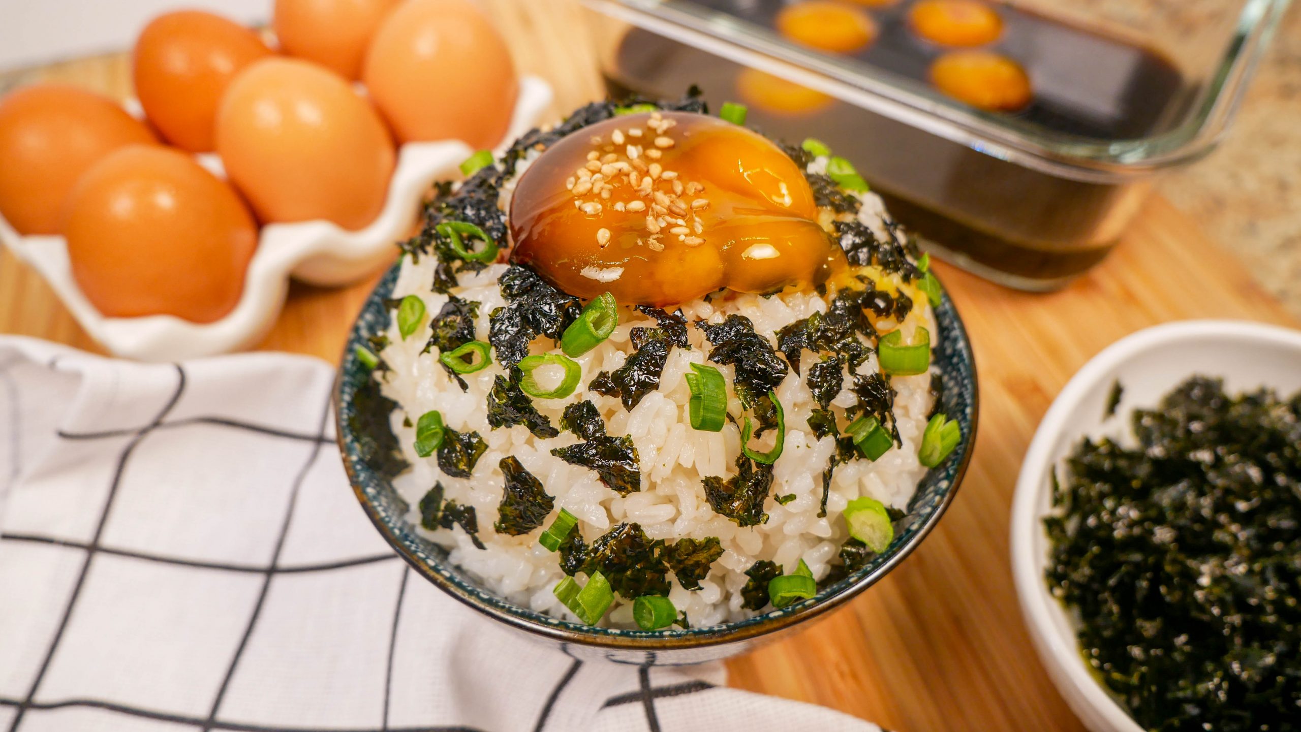 soy cured egg yolks on top of a bed of rice with scallions and nori seaweed