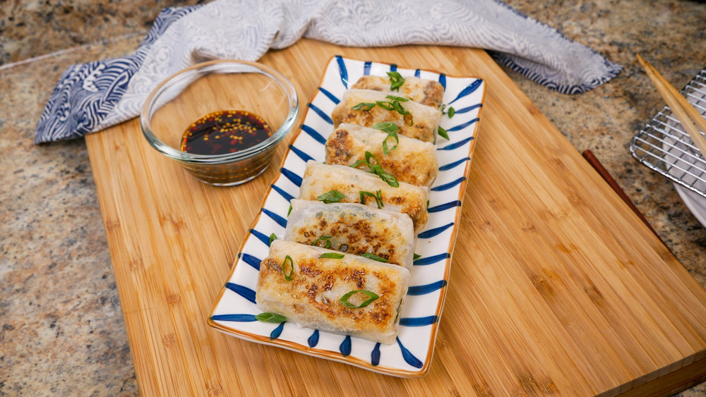 tuna cabbage rice paper dumplings with dipping sauce on cutting board