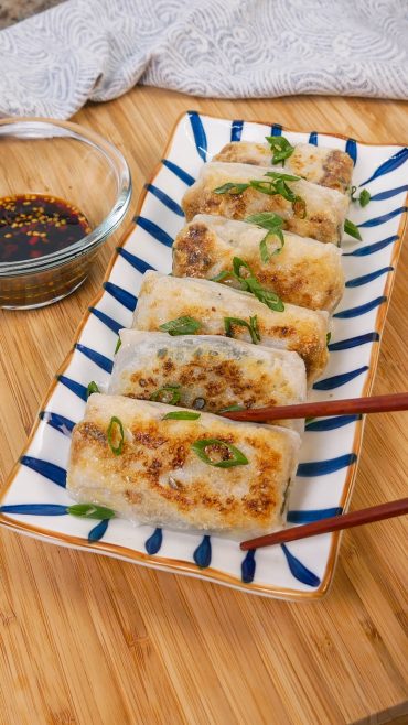 chopsticks holding up tuna cabbage rice paper dumplings with dipping sauce